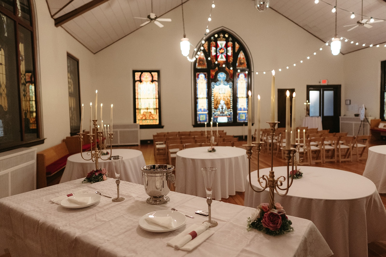 The Sanctuary set with candlelit tables beneath original stained-glass windows